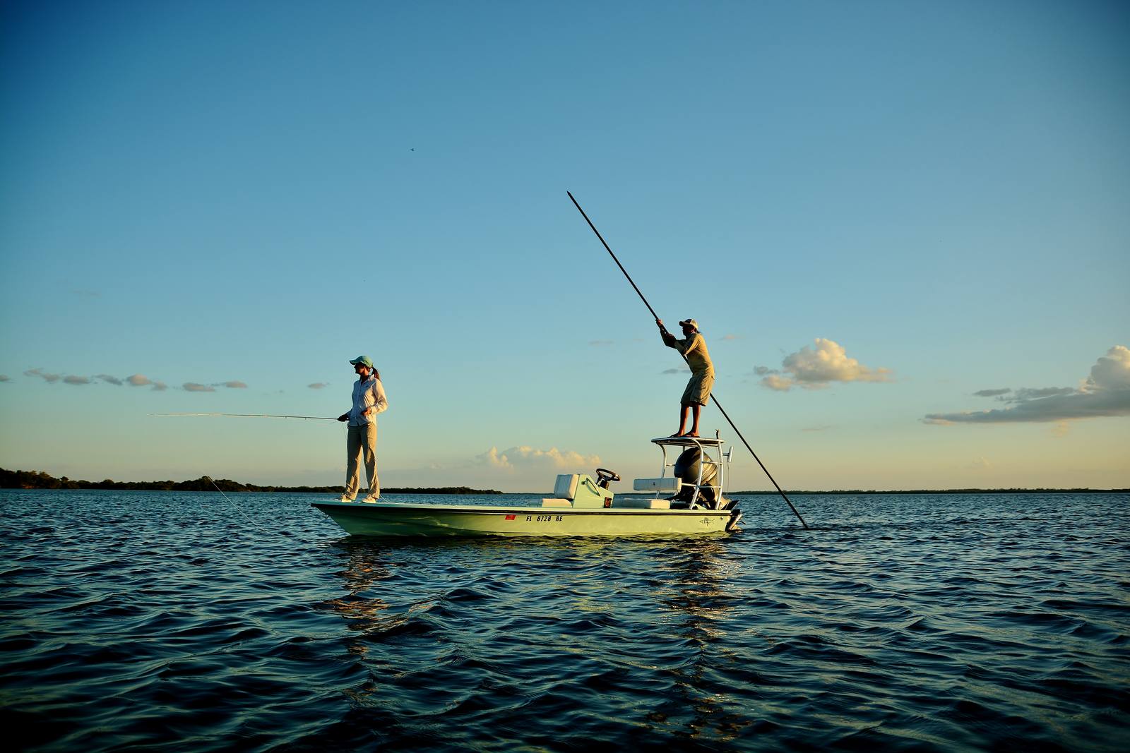 Two anglers on the bow of a poled flats skiff, casting on Pine Island Sound