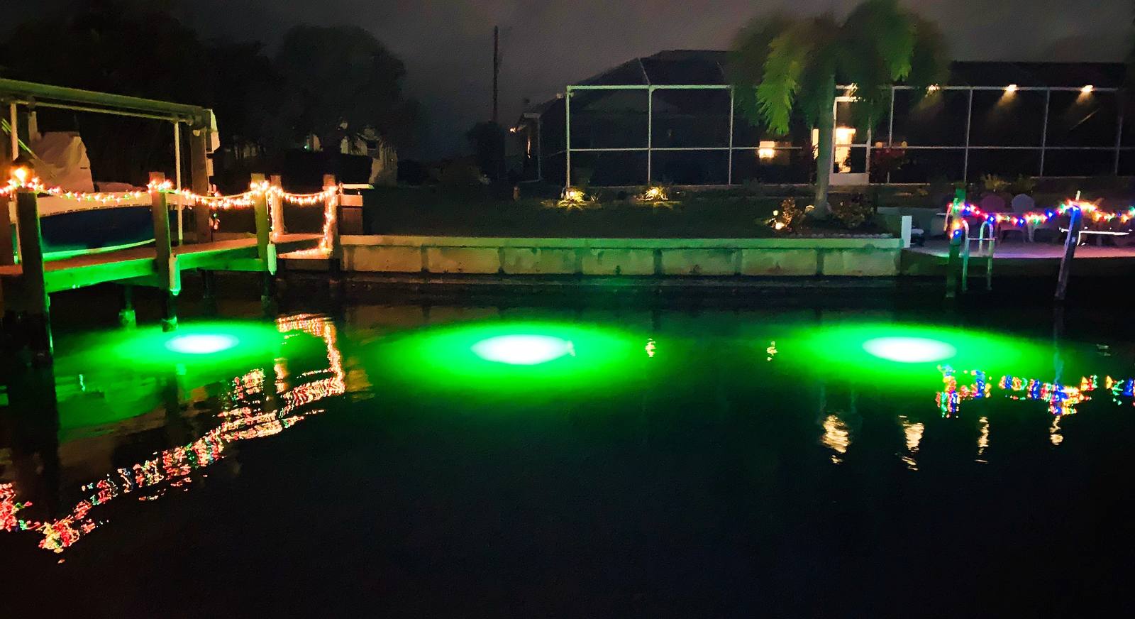 A row of green dock lights glowing across a canal at night